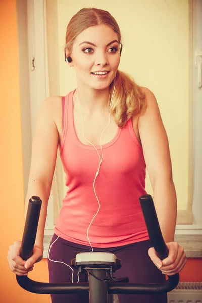 Γυναίκα στην άσκηση ποδήλατο ακούγοντας μουσική. Γυμναστήριο — Φωτογραφία Αρχείου