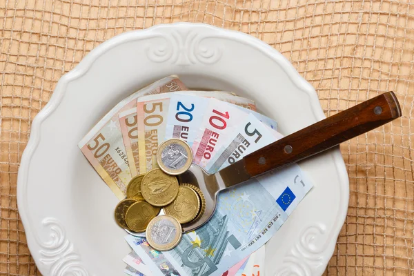 Тарелка, ложка с монетами и банкнотами — стоковое фото