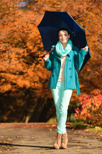 Mädchen spaziert mit blauem Regenschirm durch herbstlichen Park — Stockfoto