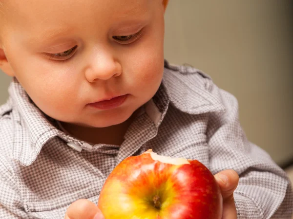 男孩吃苹果在家里. — 图库照片