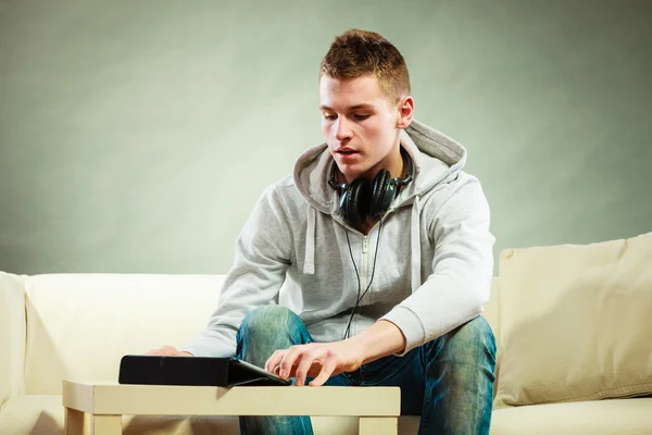 Man with headphones sitting on couch — Stock Photo, Image