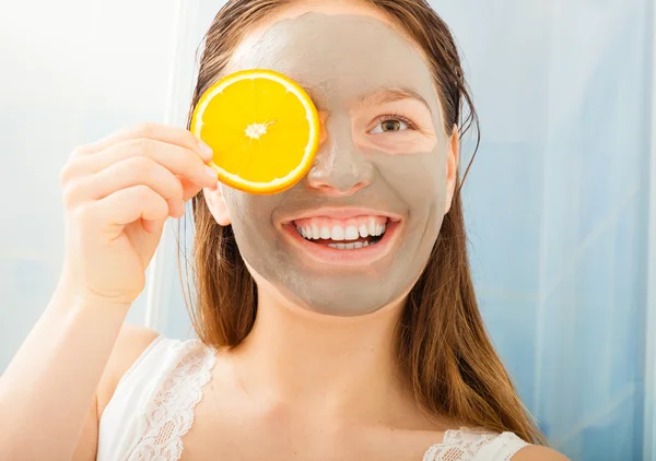 Mujer con rebanada de naranja y máscara de barro — Foto de Stock