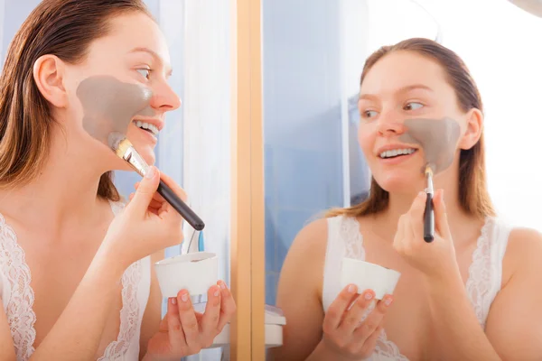 Woman applying mud facial mask — Stock Photo, Image