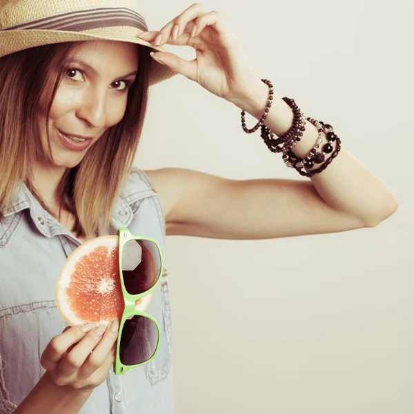 Lycklig kvinna i hatt innehar solglasögon och grapefrukt — Stockfoto