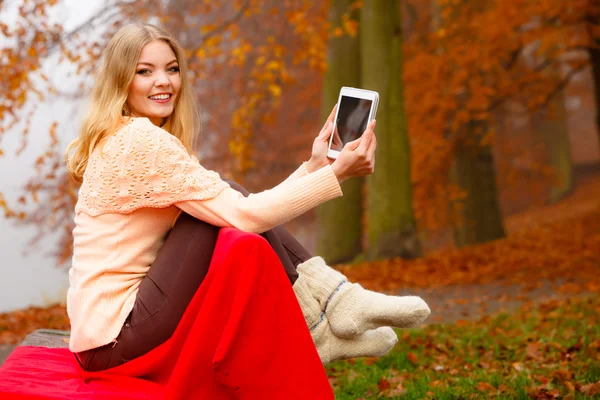 Женщина в осеннем парке с помощью планшета — стоковое фото