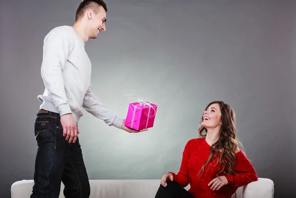 Man surprising cheerful woman with gift box — Stock fotografie