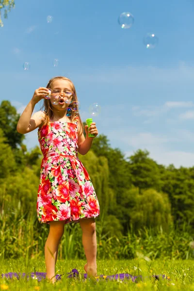Menina criança soprando bolhas de sabão ao ar livre . — Fotografia de Stock