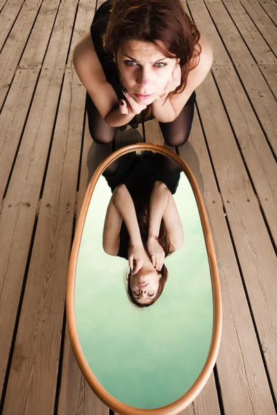 Thoughtful woman looks at reflection in mirror — Stock Photo, Image