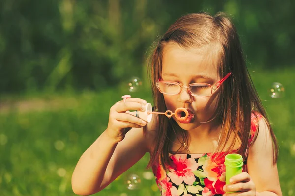 Lilla flickan barnet blåser såpbubblor utomhus. — Stockfoto