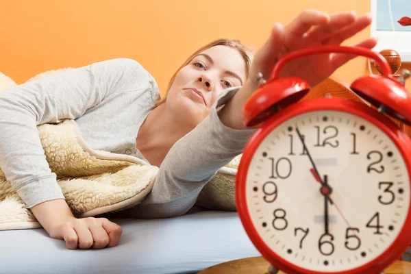 Woman waking up turning off alarm clock in morning — Stock Photo, Image