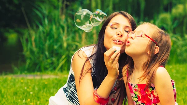 Mother and girl blowing soap bubbles — Stock Photo, Image