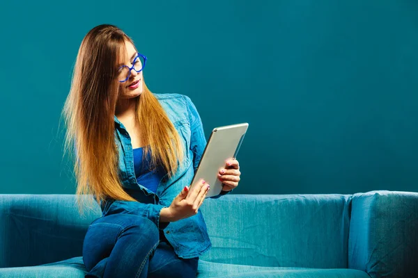 Kvinna med tablett sitter på soffa blå färg — Stockfoto