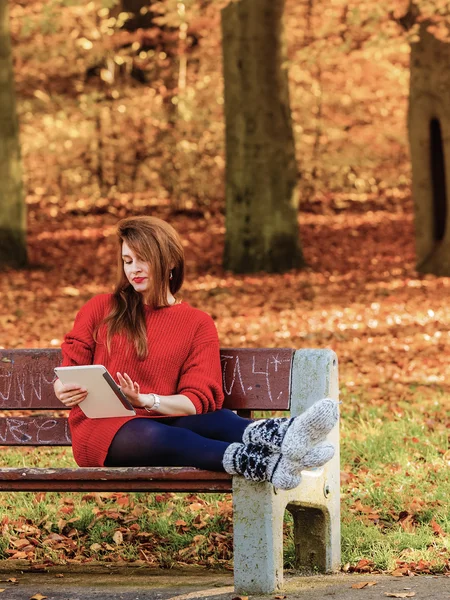 Женщина в осеннем парке с помощью планшетного компьютера . — стоковое фото