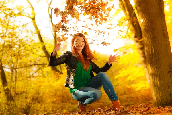 Girl relaxing in autumn park throwing leaves up in the air. — Stock Photo, Image