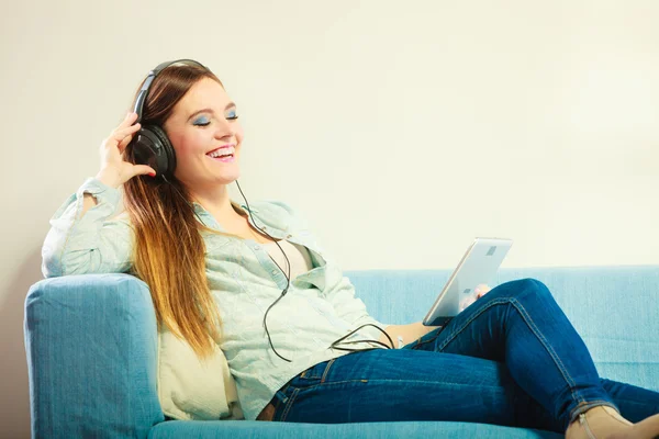 Frau mit Tablet-Kopfhörer sitzt auf Couch — Stockfoto