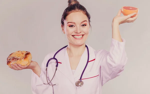 Feliz nutricionista segurando frutas e bolo — Fotografia de Stock