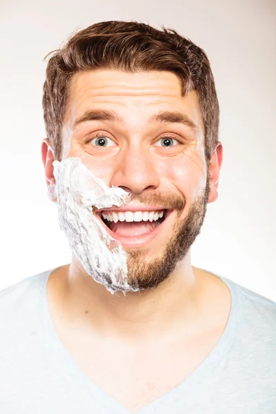 Happy man with shaving cream foam on half of face. — Stock Photo, Image