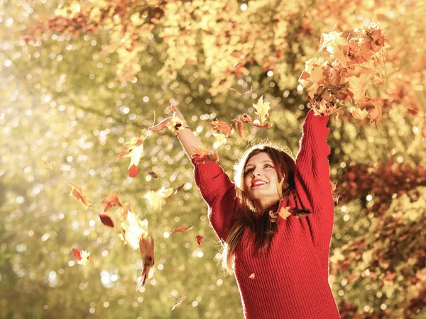 Žena v podzimním parku házení nechává se ve vzduchu — Stock fotografie