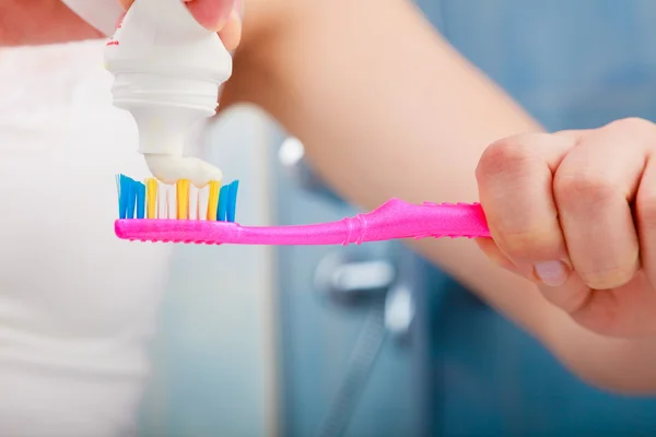 Woman hands putting toothpaste on toothbrush — Stock Photo, Image