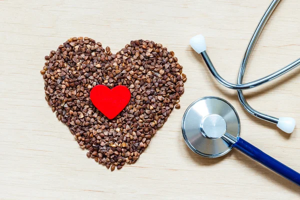 Buckwheat groats heart shaped on wooden surface. — Stock Photo, Image