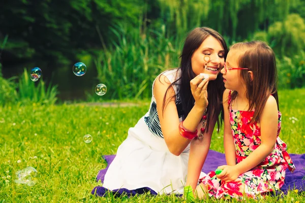 Mother and child blowing soap bubbles outdoor. — Stock Photo, Image