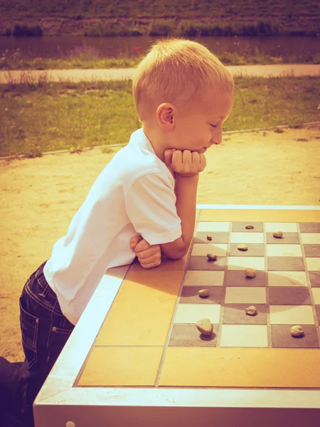 Little boy clever child playing checkers in park — Stock Photo, Image