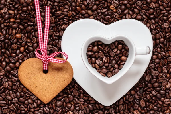 Tazza a forma di cuore e biscotti su sfondo chicchi di caffè — Foto Stock
