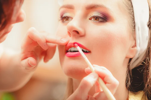Visagistin trägt Lippenstift mit Pinsel auf. — Stockfoto