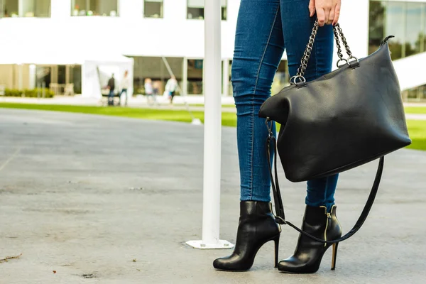 De benen van de vrouw in hakken schoenen handtas in de hand — Stockfoto