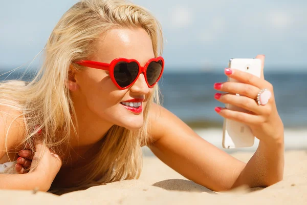 Woman using smartphone on beach — Stock Photo, Image