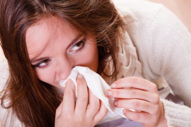 woman with fever sneezing in tissue clipart
