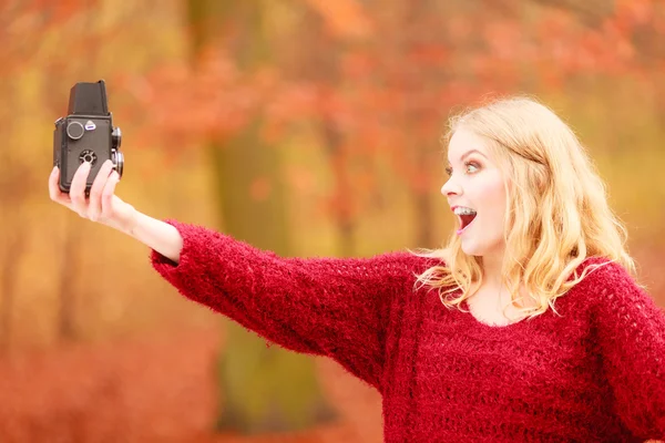 Mujer sonriente sosteniendo la cámara vintage . — Foto de Stock