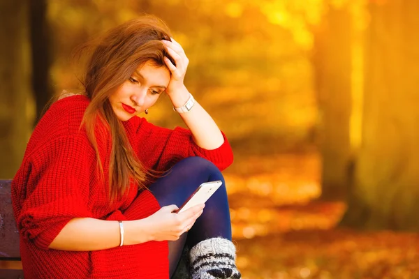 Грустная расстроенная девушка с мобильным телефоном в осеннем парке — стоковое фото