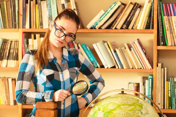 Chica en la biblioteca con globo y lupa —  Fotos de Stock