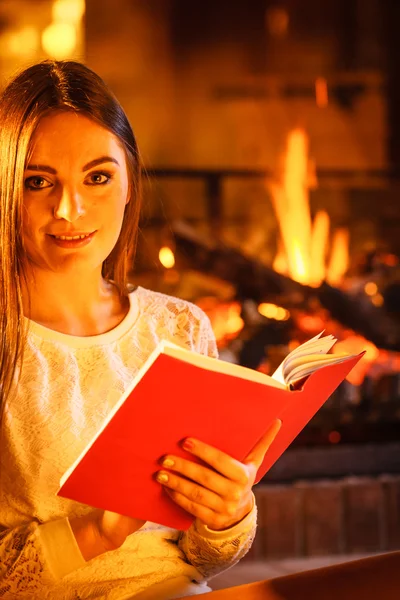 Женщина читает книгу у камина. Зимний отдых дома — стоковое фото