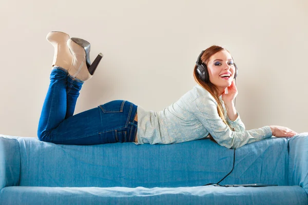 Woman with tablet headphones laying on couch — Stock Photo, Image