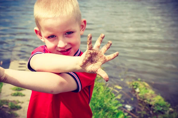 Niño jugando al aire libre mostrando sucias manos fangosas . —  Fotos de Stock