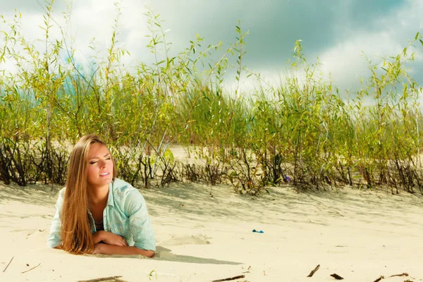 Jeune femme couchée sur une dune herbeuse — Photo