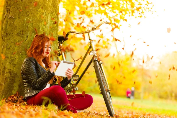Kadın sonbahar Park kullanarak tablet bilgisayarda okuma — Stok fotoğraf