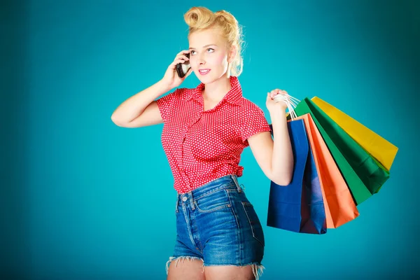 Pinup menina com sacos de compras chamando no telefone — Fotografia de Stock