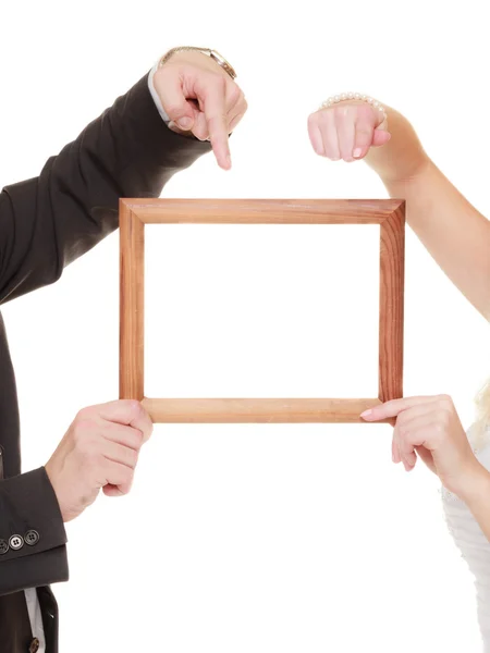 Wedding couple pointing empty frame for photos. — Stockfoto