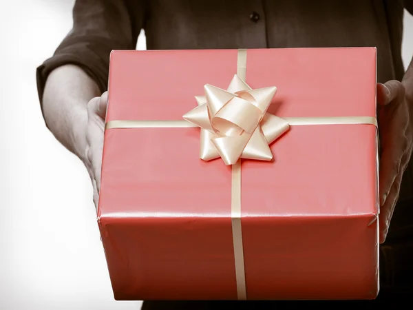 Férias. Homem dando caixa de presente vermelho com fita dourada — Fotografia de Stock