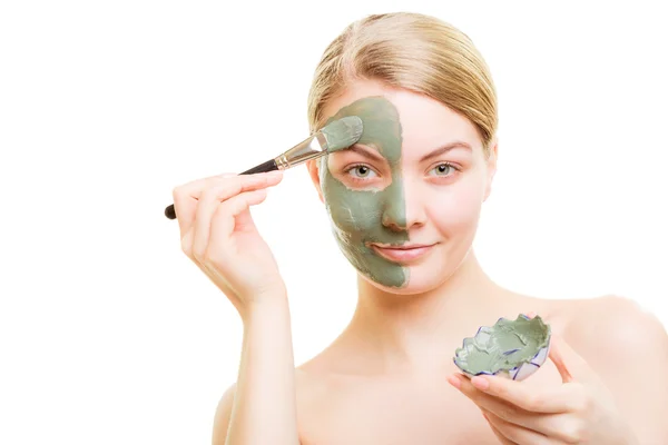 Chica aplicando mascarilla de arcilla facial en su cara — Foto de Stock