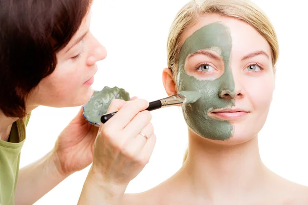 Cosmetician tillämpar lera ansiktsmask på kvinna ansikte. — Stockfoto