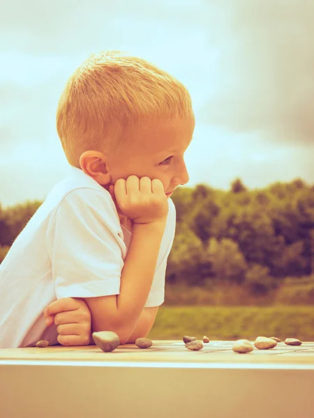 Petit garçon intelligent enfant jouer dames dans le parc — Photo