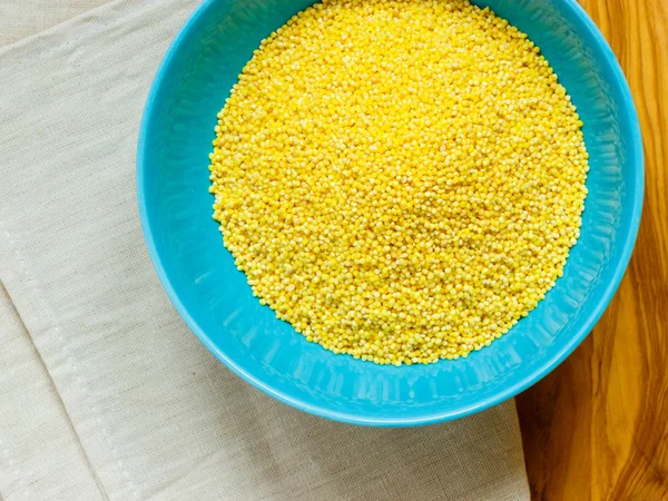 Millet groats in blue bowl on wooden table — Stock Photo, Image