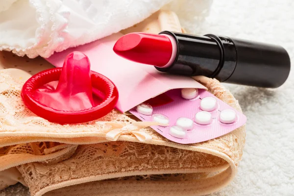 Pills condom and lipstick on lace lingerie — Stock Photo, Image