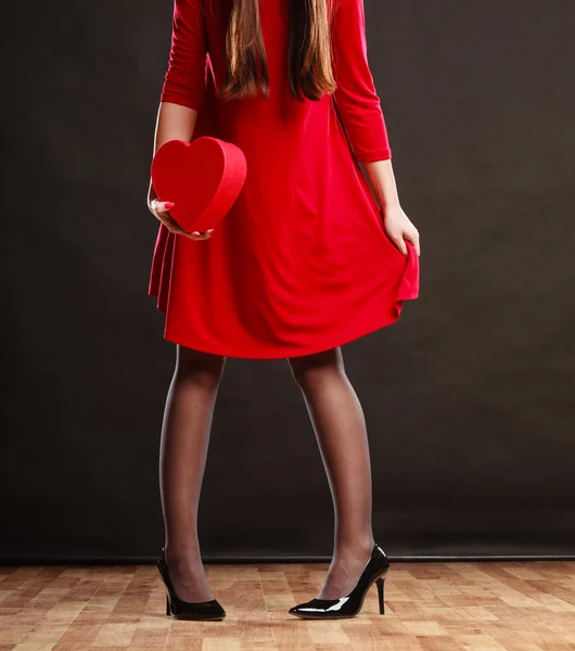 Mulher de vestido vermelho segurando caixa de coração. — Fotografia de Stock