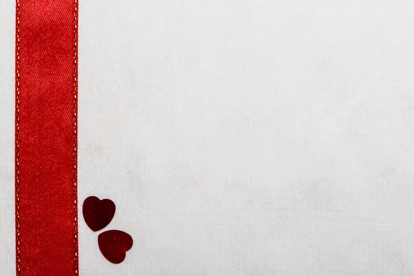 Red satin ribbon hearts on white cloth. — Stock Photo, Image