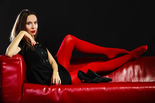 Mode kvinna i röda strumpbyxor på soffan — Stockfoto